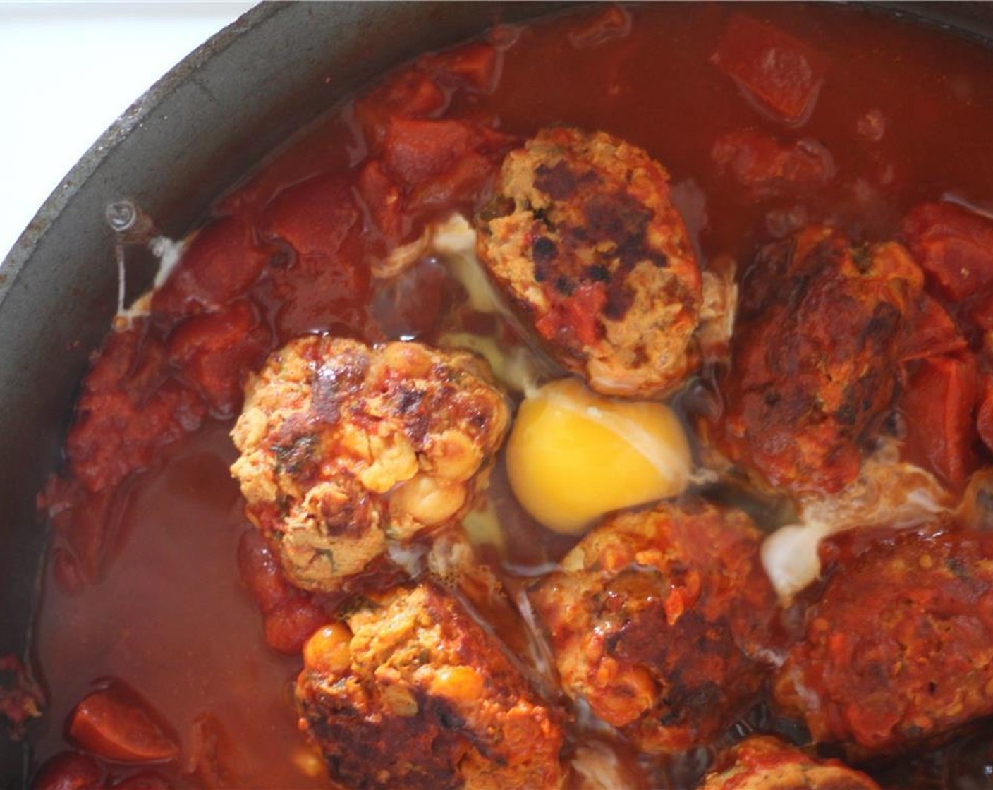 step 6 When it is ready for serving, crack the Eggs (4) over the meatballs. Make sure not to break the yolks. Cover again and cook until the eggs are poached, with a runny yolk.