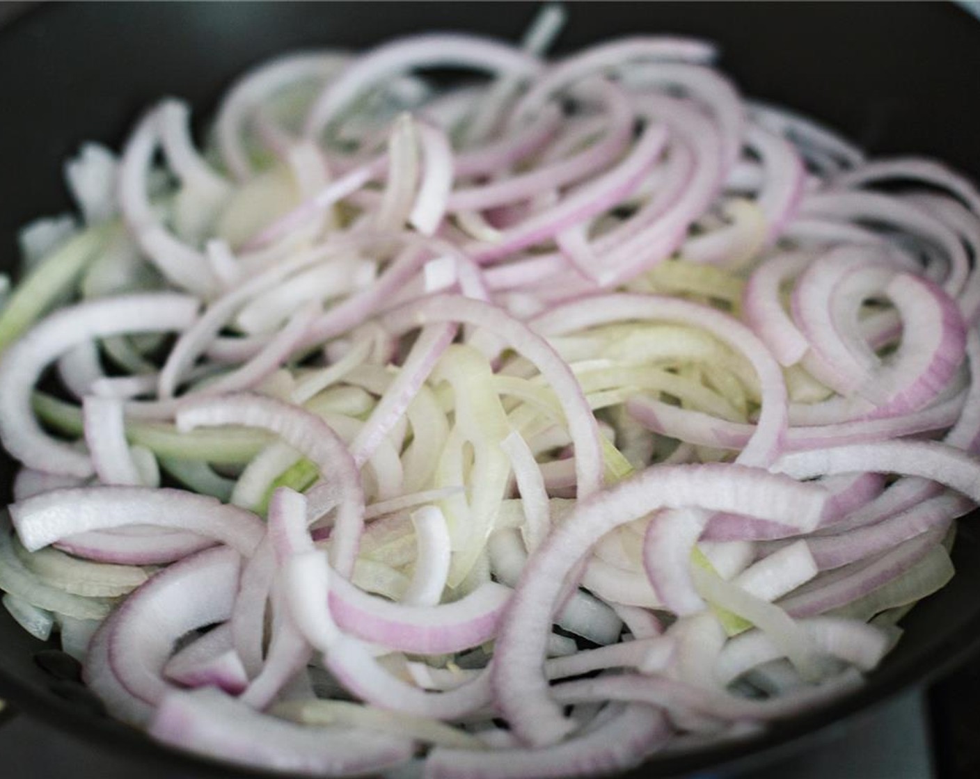 step 7 Heat up Olive Oil (2 Tbsp) in a skillet and add thinly sliced Red Onions (2).
