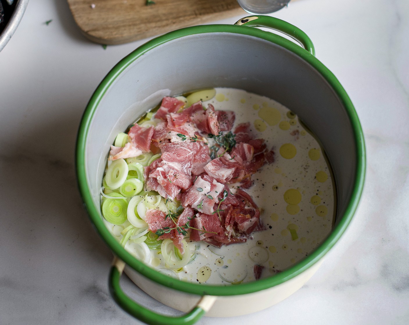 step 5 Place the casserole dish over medium coals and add a glug of Olive Oil (2 Tbsp). Crisp up the Shoulder Bacon (7 oz) before adding the Leeks (2) and Garlic (3 cloves) and sautéing until soft.