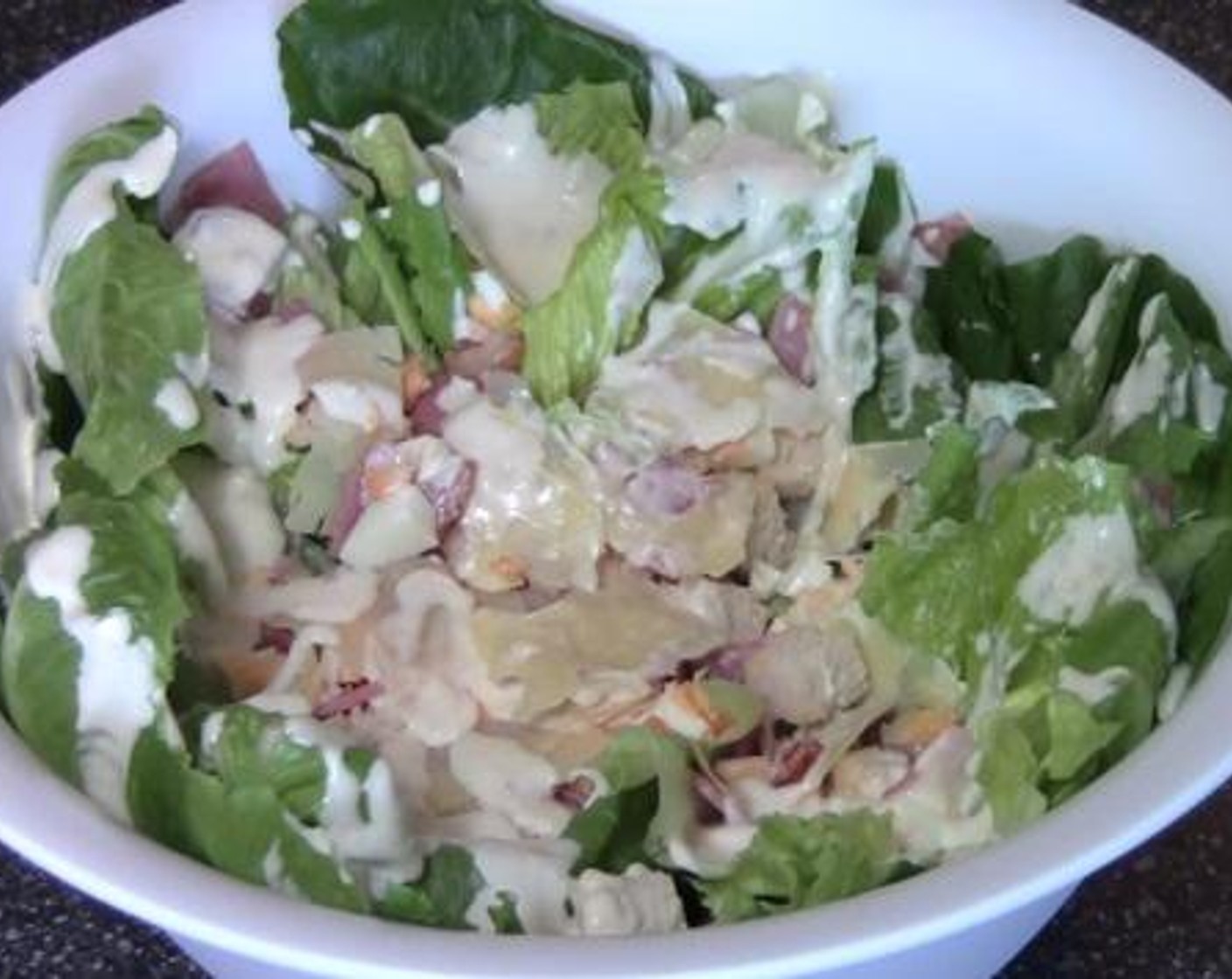step 5 In a large salad bowl, mix together the Romaine Lettuce (1 head), croutons, bacon, Egg (1), and Shaved Parmesan Cheese (to taste). Serve after drizzling with the dressing.