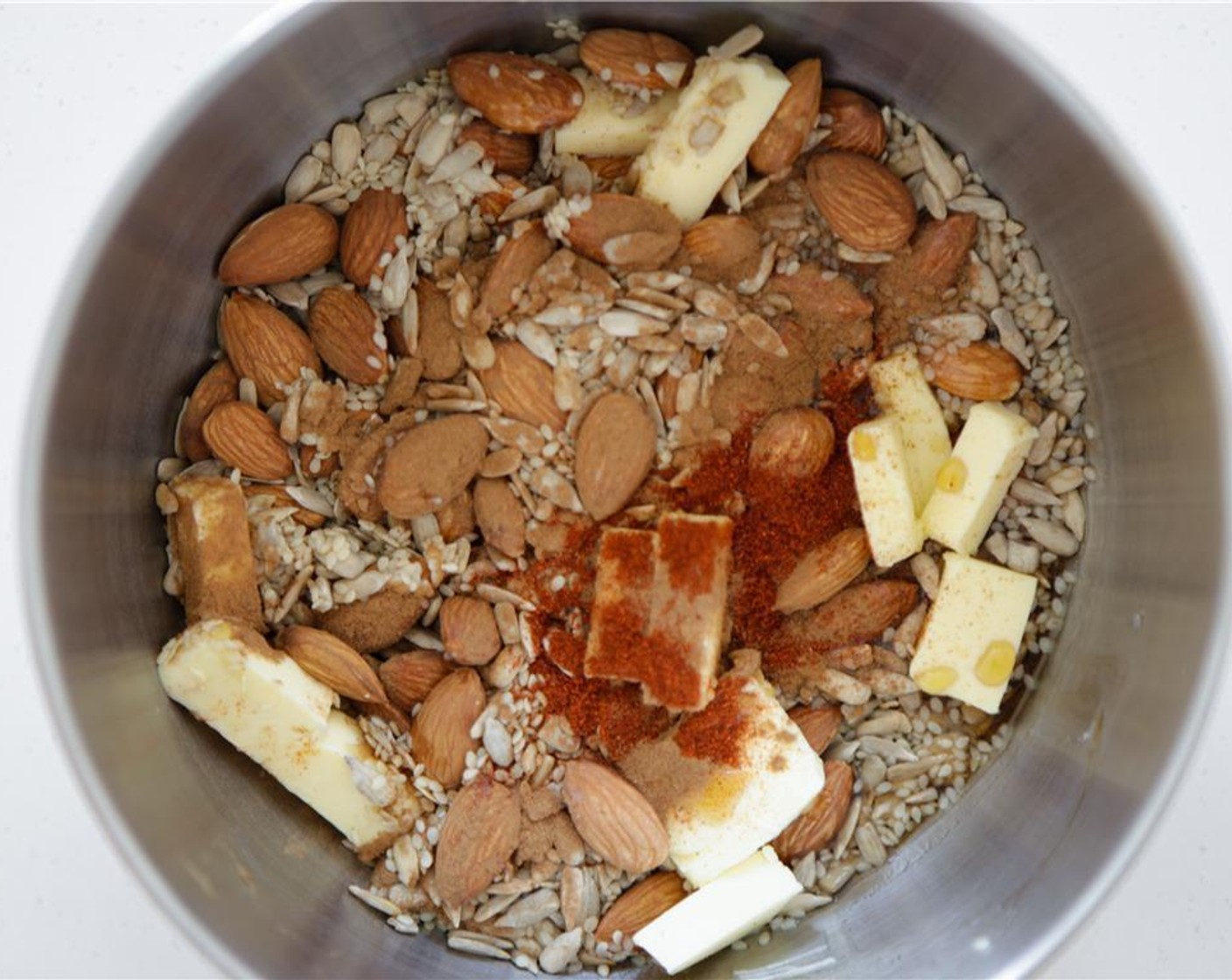 step 2 Mix Raw Almonds (1/2 cup), Pepitas (1/4 cup), Sunflower Seeds (1/4 cup), Sesame Seeds (1/4 cup), Maple Syrup (1/3 cup), Butter (2 Tbsp), Ground Cinnamon (1/4 tsp), Cayenne Pepper (1/8 tsp) and Salt (1 pinch) in a bowl.