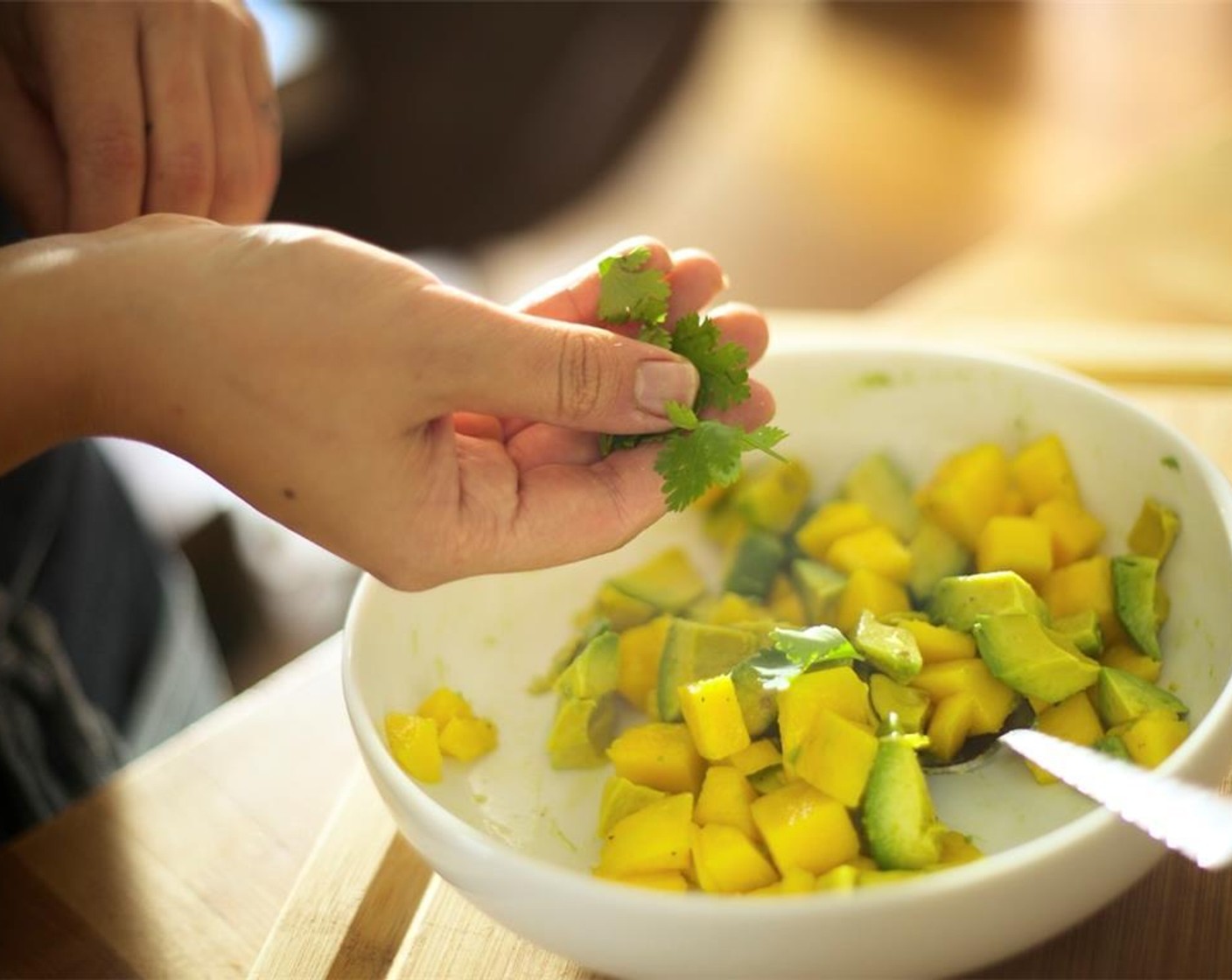 step 12 Use your knife's tip to score avocado flesh without piercing the skin, making squares, and then scoop it out into the bowl with mango. Toss together mango, avocado and half of the cilantro. Add Olive Oil (1/2 tsp), Salt (to taste) and Ground Black Pepper (to taste). Toss.