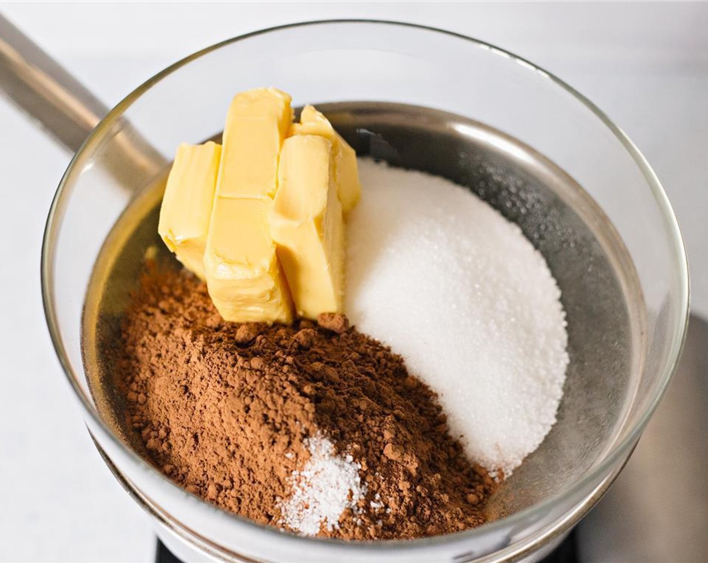 step 3 Place bowl on top of saucepan. Then add Unsweetened Cocoa Powder (3/4 cup), Unsalted Butter (2/3 cup), Granulated Sugar (1 1/4 cups), and Salt (1/4 tsp). Allow the butter to melt completely.