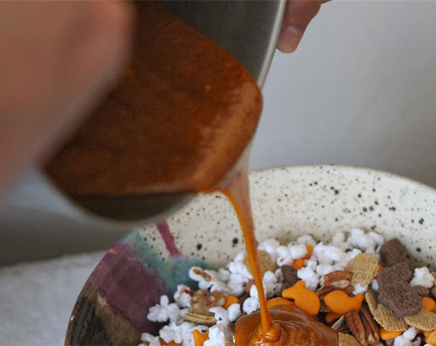 step 8 Pour the caramel mixture over 1 bowl of the mix. Stir and spread the caramel over the mixture as evenly as you can. Spread mixture onto a large sheet cake pan (18x26) that has been covered with parchment paper.