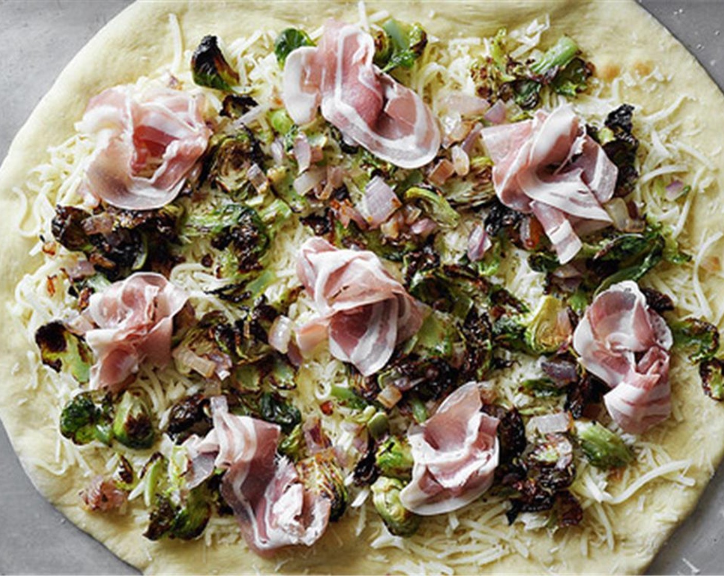 step 13 Top with the crispy brussels sprout leaves and sautéed red onion. Lay a couple slices of pancetta on each pizza. Bake for about 5 minutes to melt the cheese and continue to brown the crust.