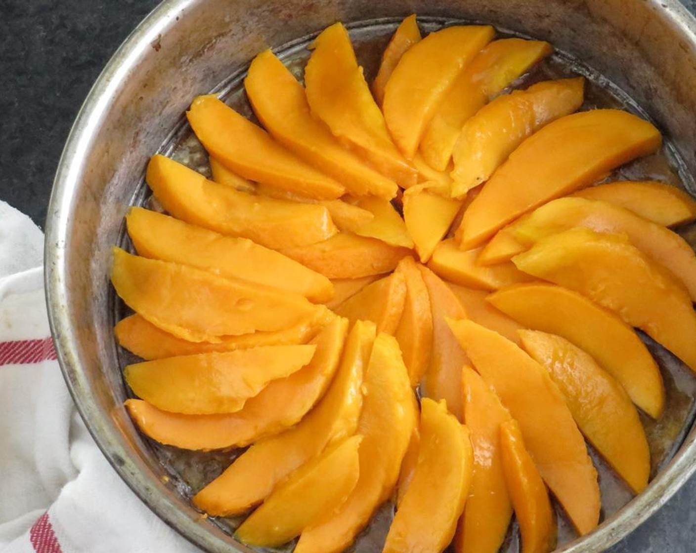 step 2 Melt Unsalted Butter (4 Tbsp) and pour into the bottom of a springform pan. Sprinkle Brown Sugar (1/3 cup) evenly over the bottom of the pan. Arrange the mangoes in a sunshine pattern along the bottom of the pan, overlapping as you go.