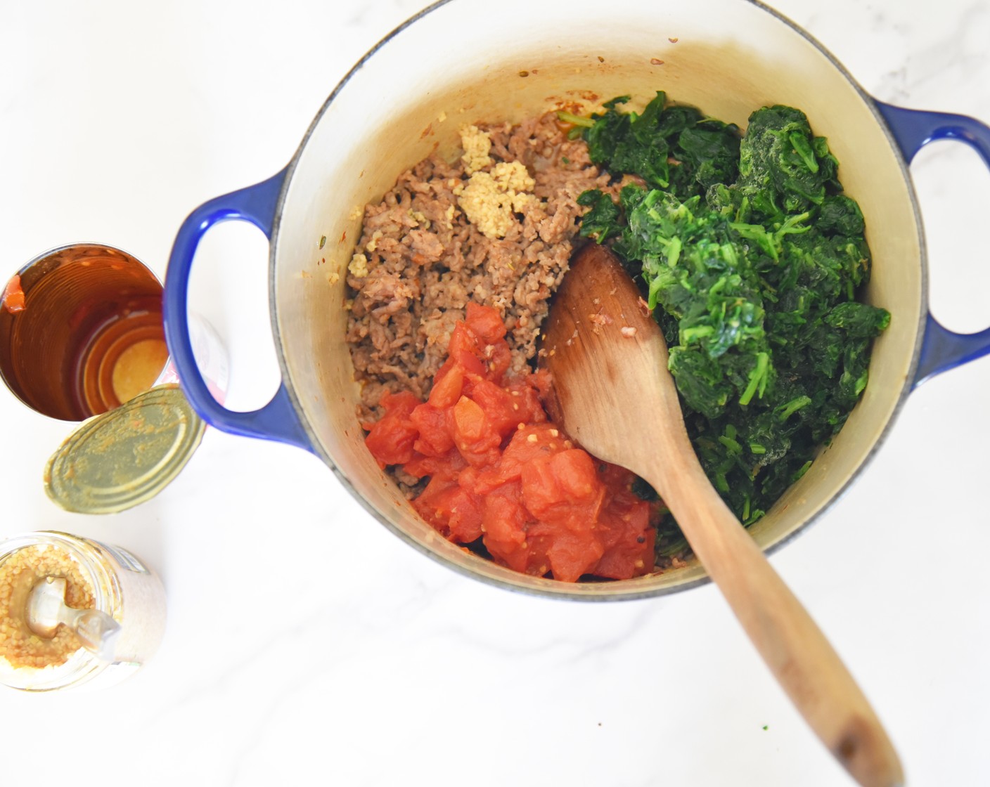 step 3 Once the meat is browned add in the Jarred Minced Garlic (1 tsp), Fire Roasted Diced Tomatoes (1 can) and their juices, Kosher Salt (1/2 tsp), and Frozen Spinach (1 pckg). Stir to combine with the meat.