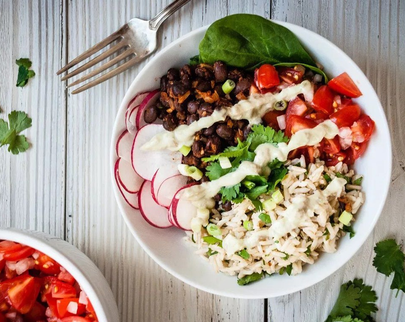 step 12 Divide cilantro rice, a small handful of Spinach Leaves (2 cups), smoky black beans, salsa, radishes, avocado crema, additional cilantro and a lime wedge between four to six bowls. Season with Queso Fresco (to taste). Enjoy on its own or with tortilla chips!