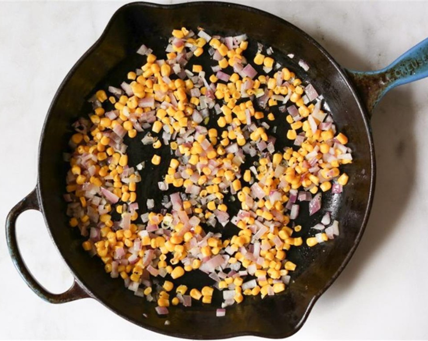 step 3 Heat Extra-Virgin Olive Oil (1 Tbsp) in a ovenproof skillet. Transfer the quinoa mixture to medium baking dish before putting it in the oven. When hot, add the Sweet Corn Kernels (3/4 cup) and Red Onion (1/2).