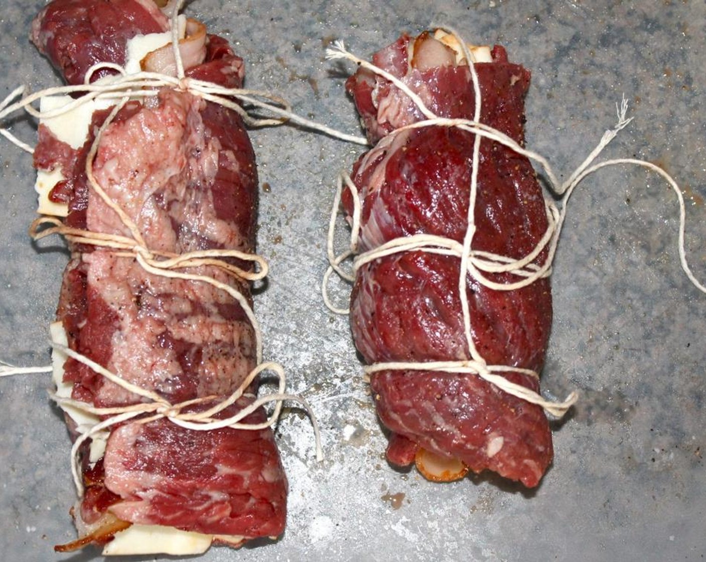 step 4 Cut cooking string. Starting from bottom edge and rolling away from you, roll beef into tight log and place on cutting board seam-side down. Starting with the middle, tie together rolled steak. Then working from center to out; tie strings on both sides.