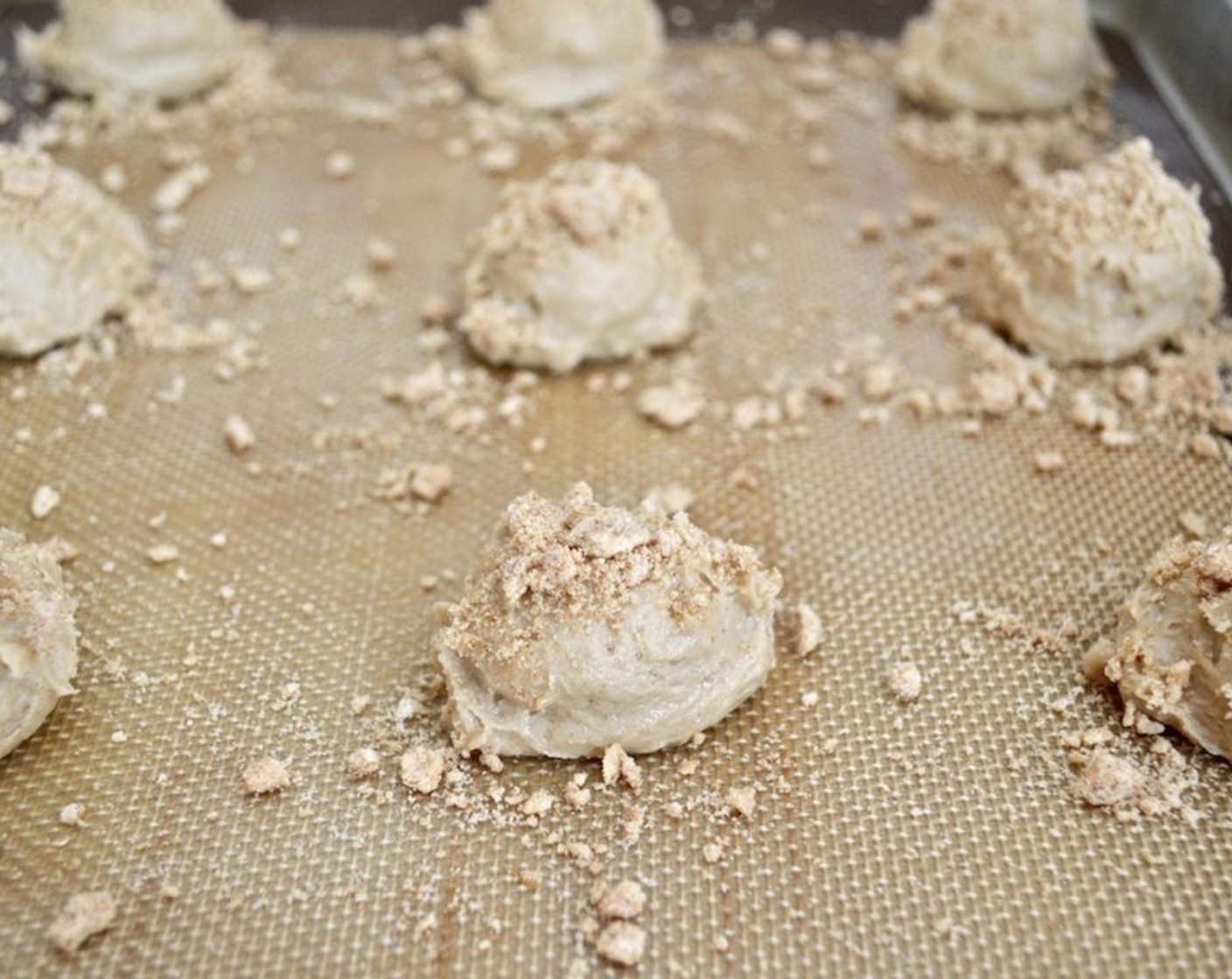 step 7 Use a heaping 1 1/2-inch cookie scoop, scoop perfect mounds of dough right onto the lined sheet trays, putting 12 on each sheet, evenly-spaced. Generously sprinkle the remaining crumbs on top of each mound of dough.