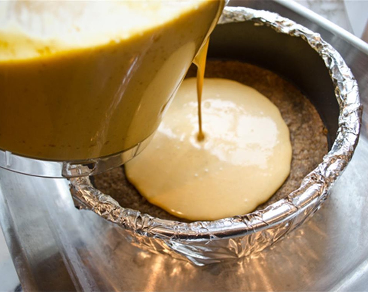 step 10 Set the cake pan in a large roasting pan. Pour the batter into the cooled crust, then pour enough boiling water into the large roasting pan to come about halfway up the side of the cake pan. Bake until the cake is just set, about 1 1/2 hours. If it jiggles, continue baking.