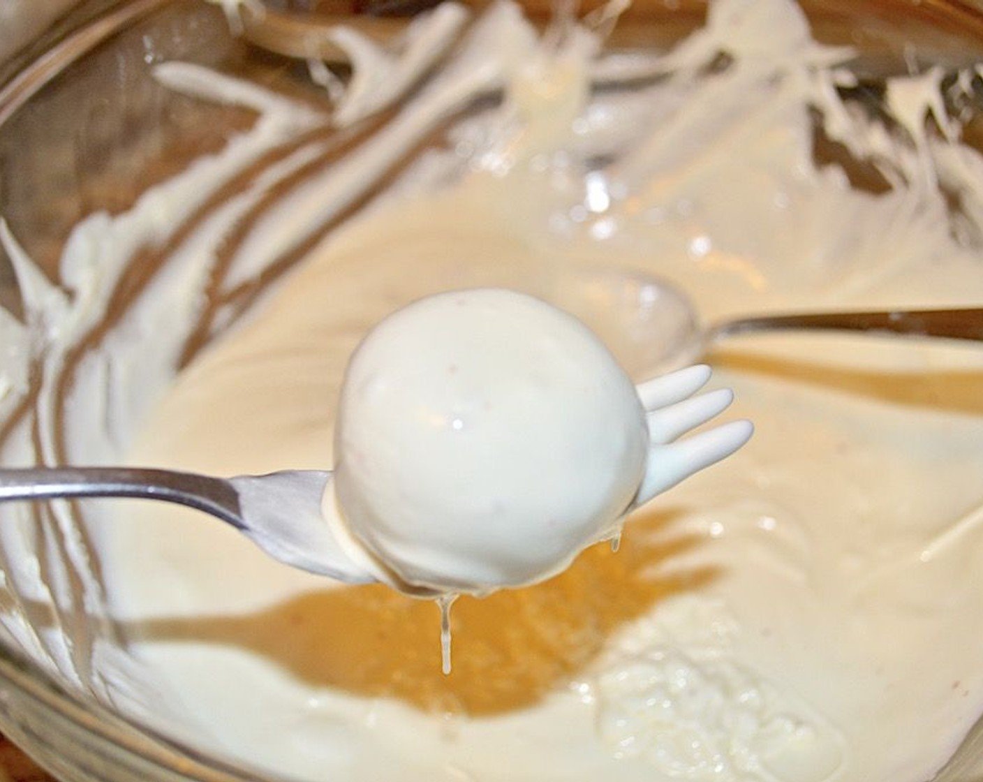 step 8 Get out the centers from chilling and place the first one on a fork above the bowl of chocolate. Spoon the chocolate over the center and gently tap the fork on the side of the bowl so that the excess drips into the bowl.