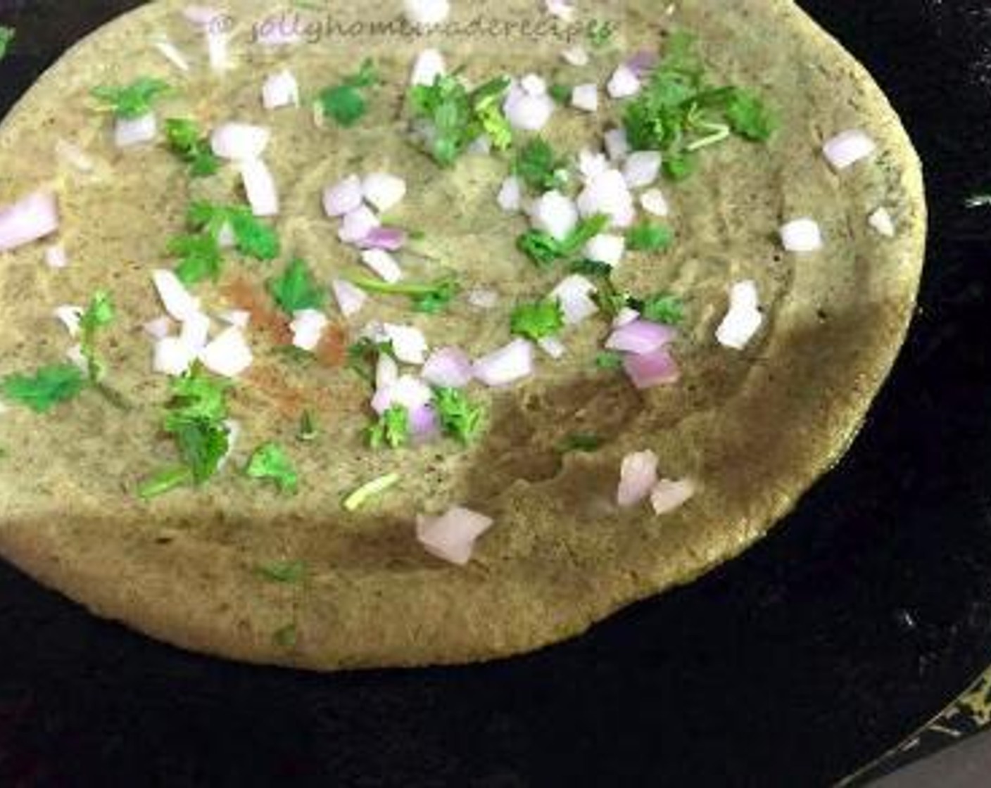 step 2 On a pan or griddle, add Oil (as needed). With a big ladle or spoon, pour the dosa batter and shape it into a round shape with the ladle. Cook the dosa on low-medium flame only. Now sprinkle some Onion (1 Tbsp) and Fresh Cilantro (1 Tbsp).