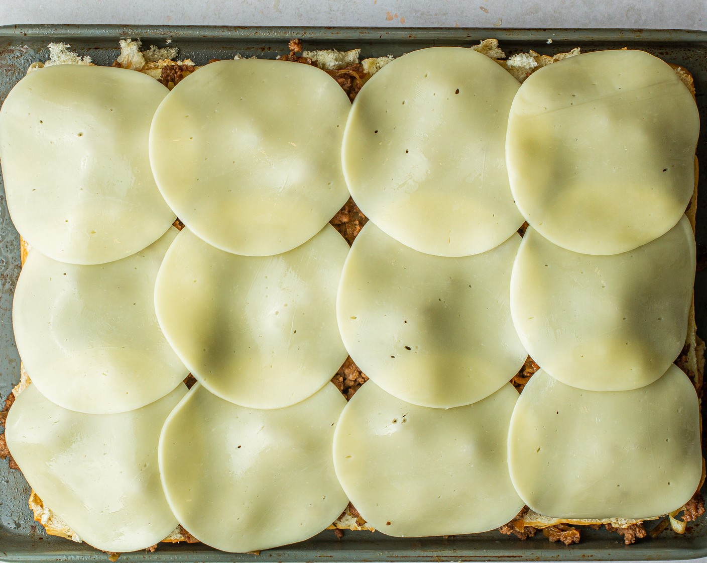 step 8 To assemble, evenly distribute the cooked onion and beef mixture over buns and evenly layer the Provolone Cheese Slice (1 cup) over the beef.