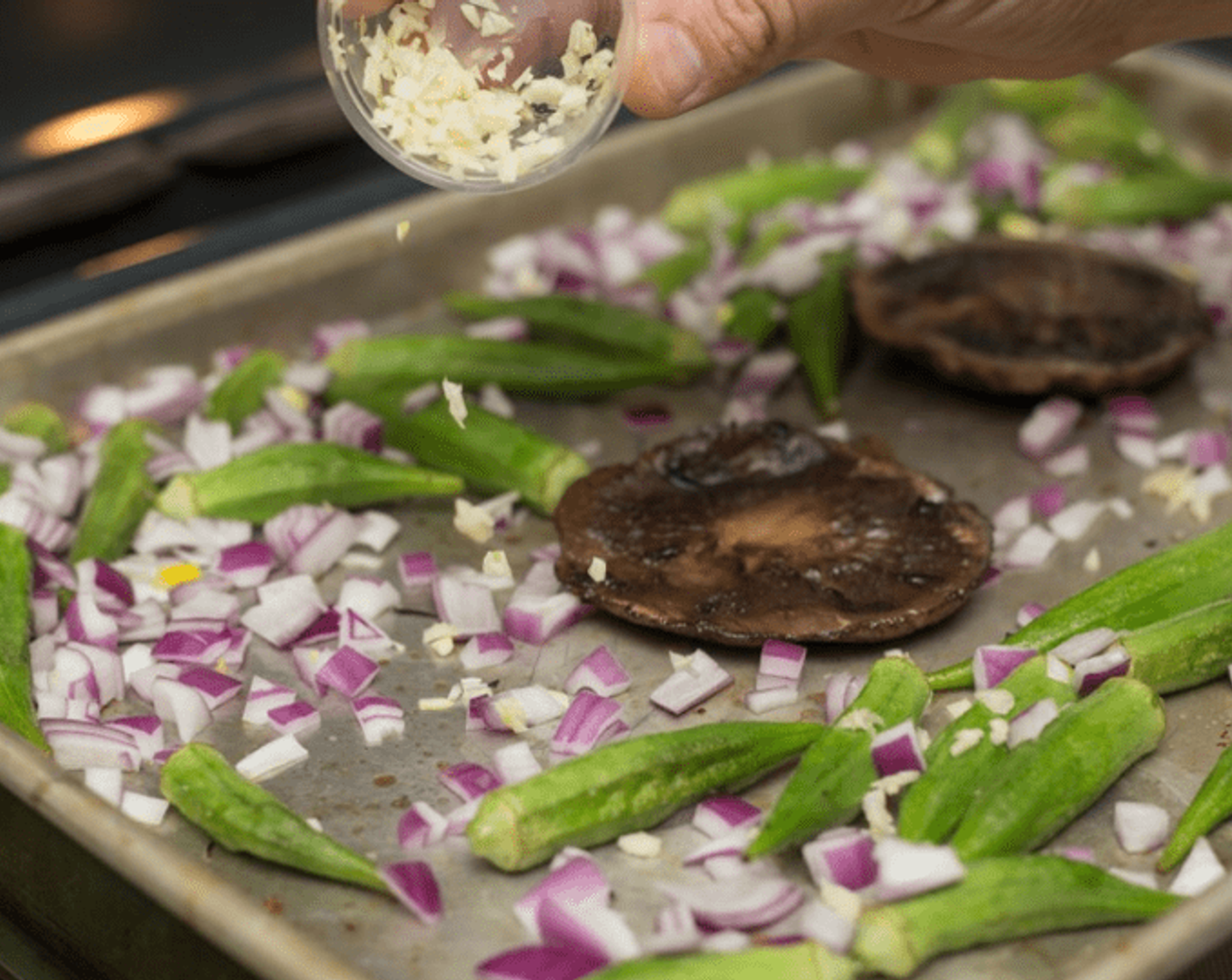 step 6 After 10 minutes, remove baking pan from oven. Flip mushroom cups, sprinkle onions, minced garlic and Dry Mixed Spice (to taste) all around the okra. Stir okra and mushrooms to incorporate. Return pan to oven and cook until onions are translucent, about an additional 10 minutes.