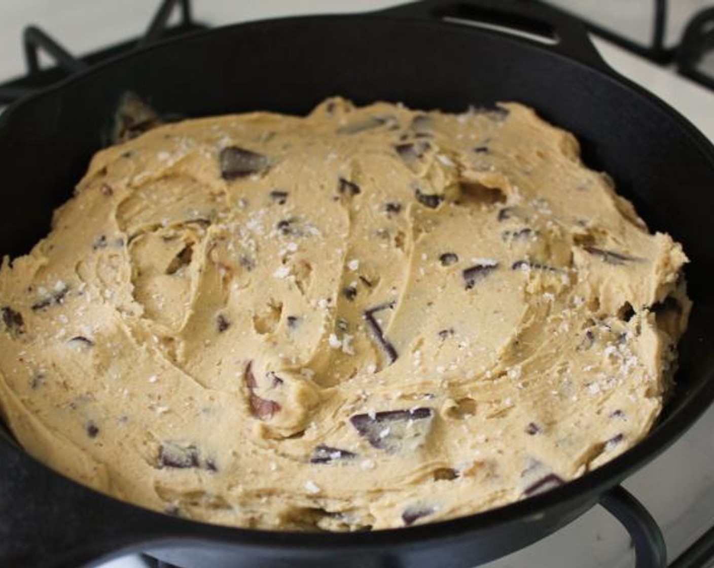 step 5 Sprinkle a large pinch of Sea Salt Flakes (to taste) over the bottom of an un-greased 10 inch cast iron skillet. Spoon the cookie batter on top and smooth the surface with a rubber spatula. Sprinkle with another pinch of sea salt and bake for 30-35 minutes, until baked through but still slightly soft in the center.