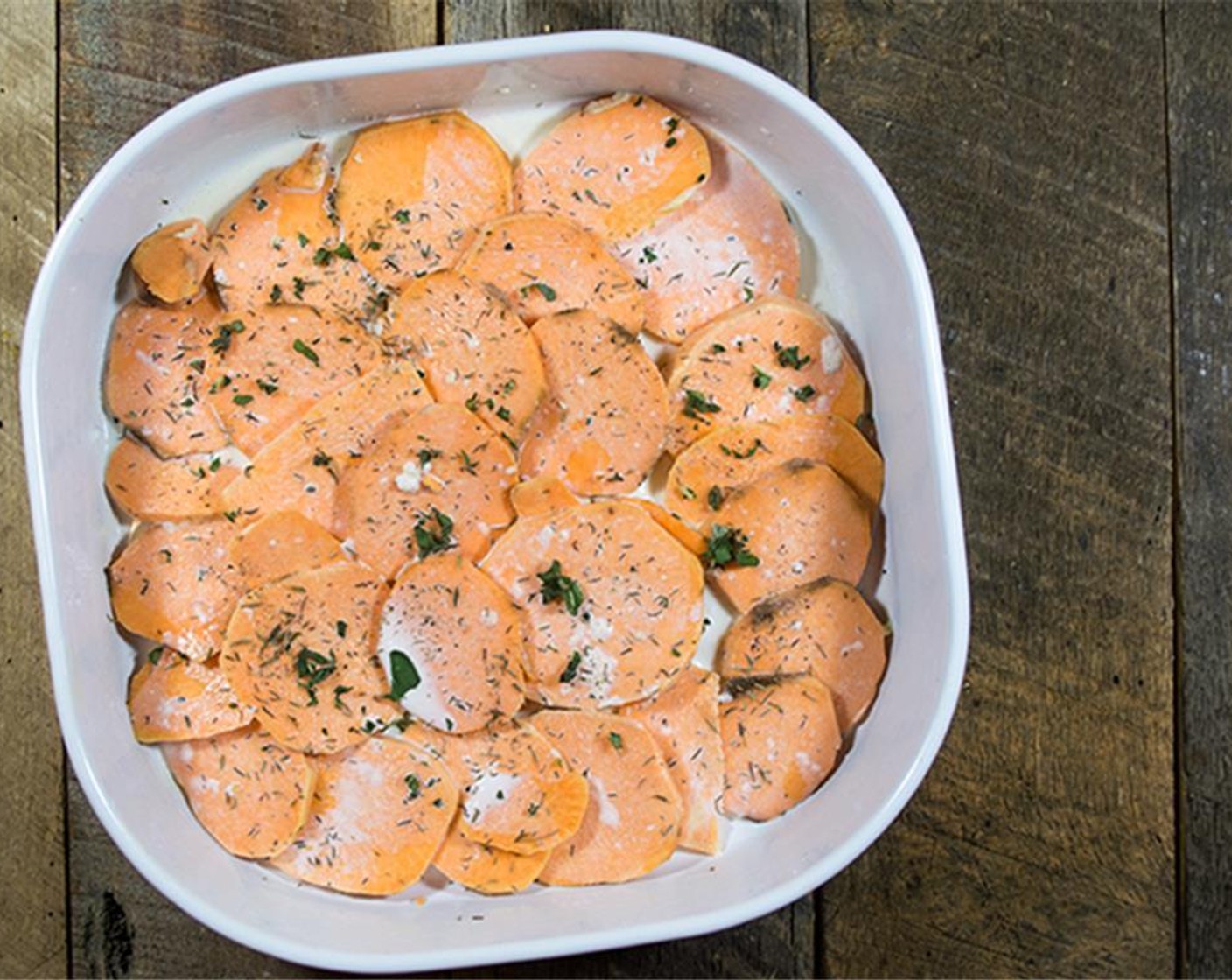 step 4 To assemble the gratin, spoon about 1/4 cup of the cream mixture into the bottom of the prepared baking dish. Place a layer of Sweet Potatoes (5), slightly overlapping in the bottom of the dish.