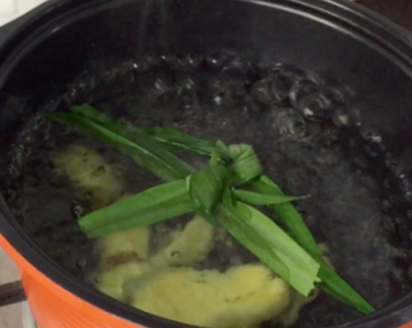 step 4 Add the crushed ginger and knotted screw pine leaves. Bring the water to a boil again.