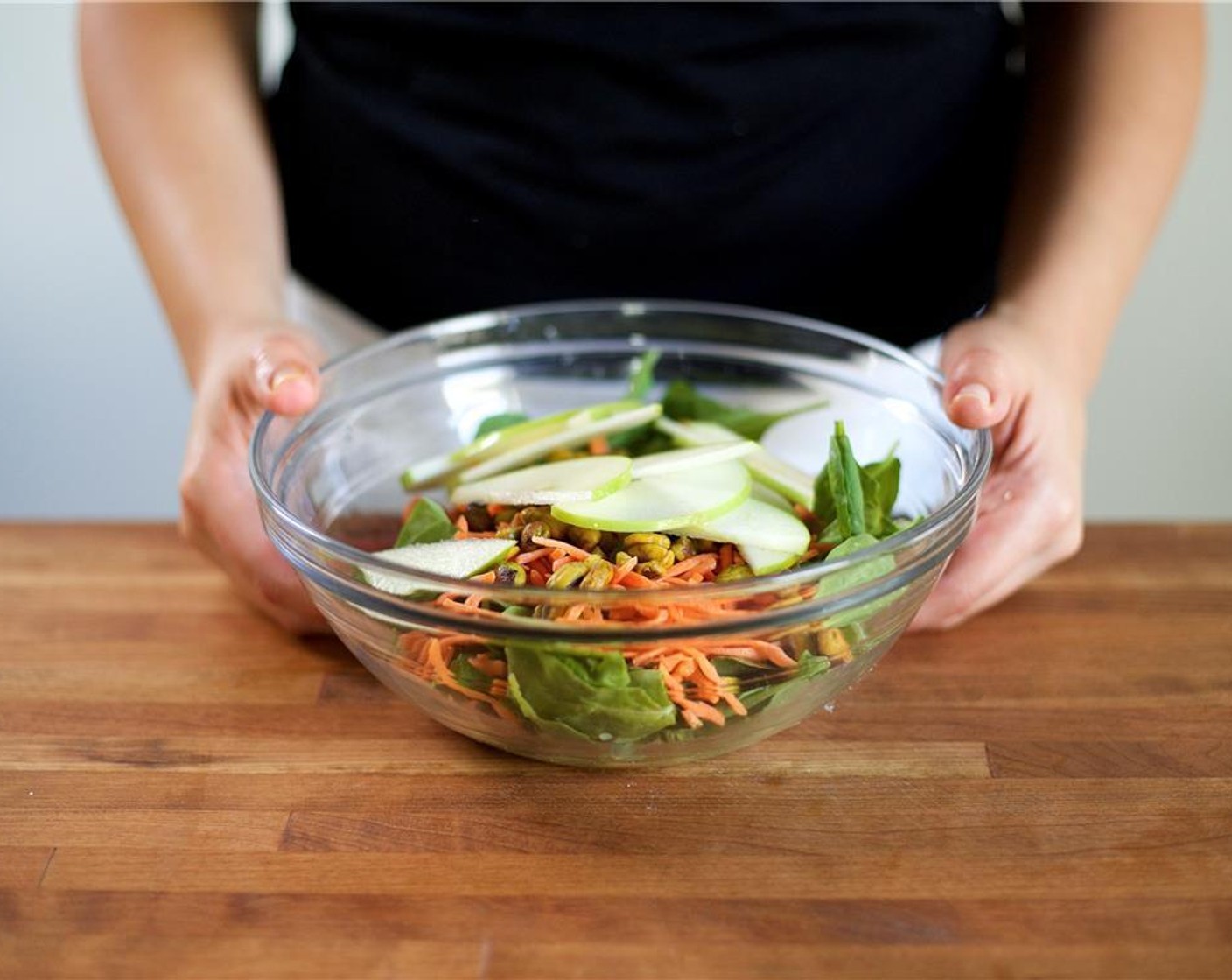 step 5 To the bowl with the vinaigrette, add the following ingredients in this order. Arugula (5 2/3 cups), matchstick carrots, Candied Pistachios (1 cup), and sliced apples.