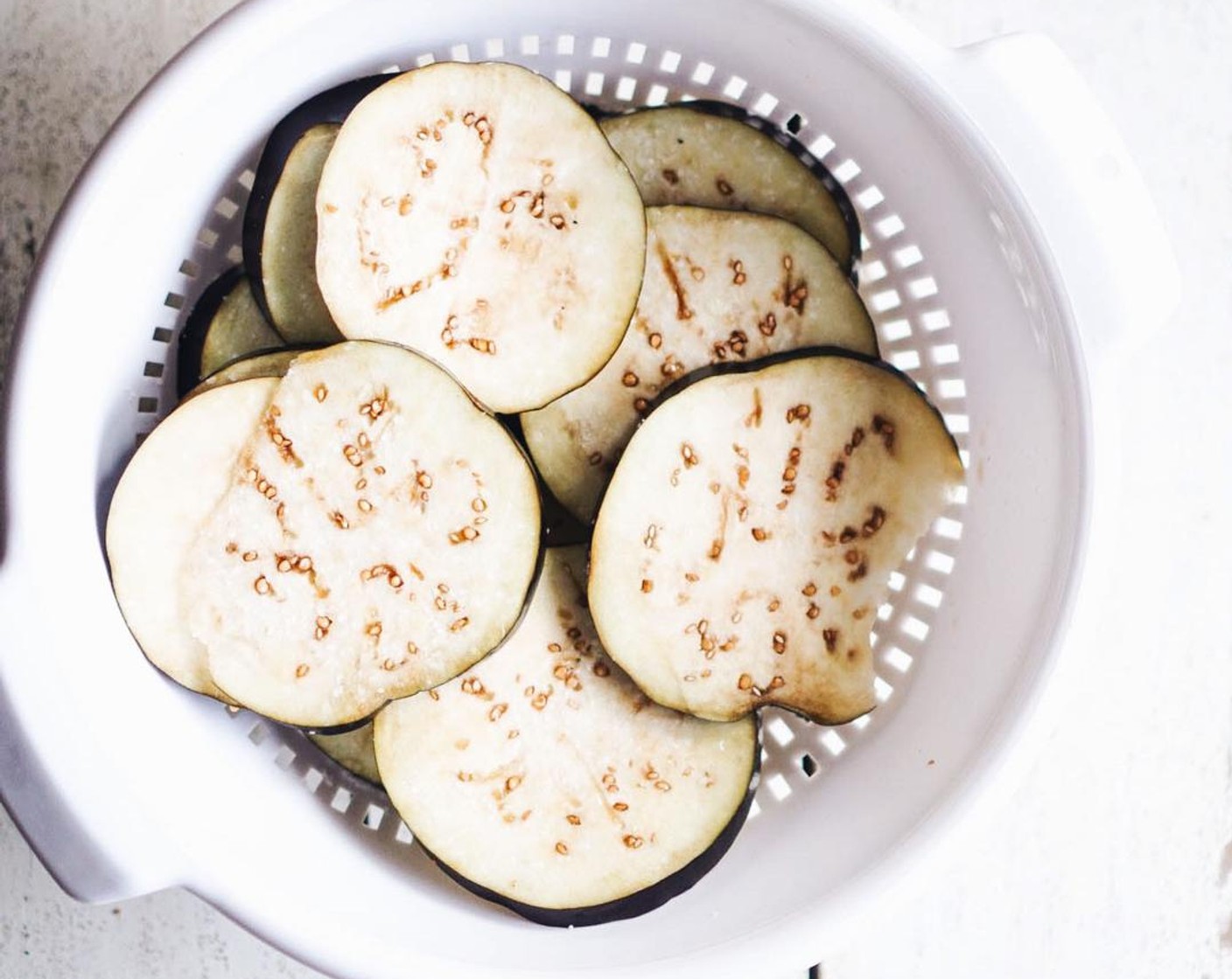 step 1 Slice the Eggplant (1) into 1/2" slices. Layer the slices in a colander, salting heavily as you go. Set side for 30 minutes, preferably over a towel or sink.