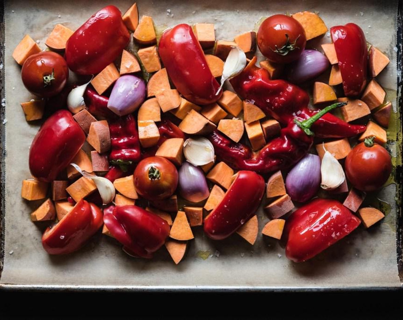 step 2 Line a large baking sheet with parchment paper. Add Red Bell Peppers (3), Sweet Potatoes (2), Yellow Onion (1), Garlic (4 cloves) and Tomatoes (2) to the baking sheet, drizzle them with the Olive Oil (1/3 cup) and sprinkle them with Salt (1/2 tsp).