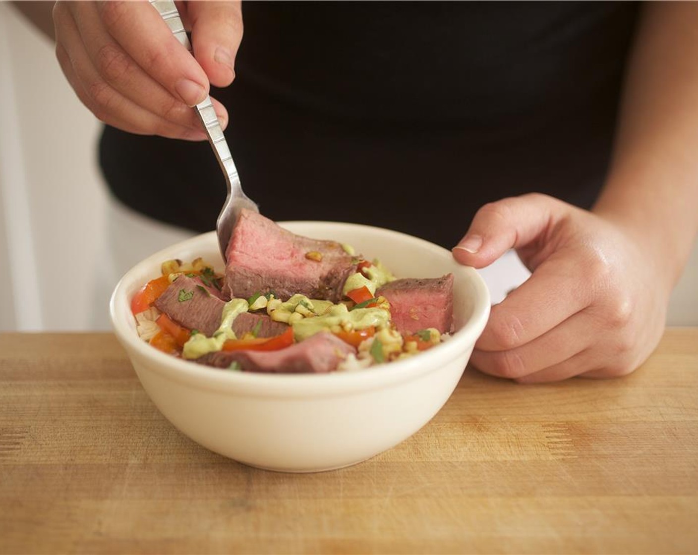 step 16 Divide the brown rice between two bowls. Add bell pepper mixture, and place steak on top. Drizzle with avocado dressing, and garnish with cilantro.