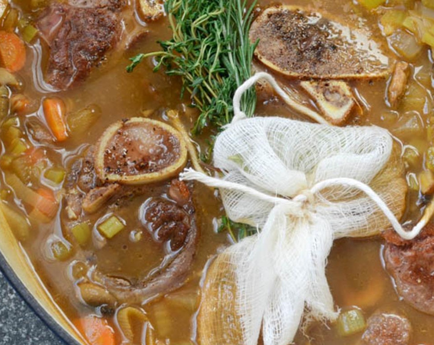 step 10 Place the bouquet garni and the herb bundle into the vegetable mix and push down into the liquid. Add the veal shanks back to the dutch oven along with any juices accumulated on the plate.