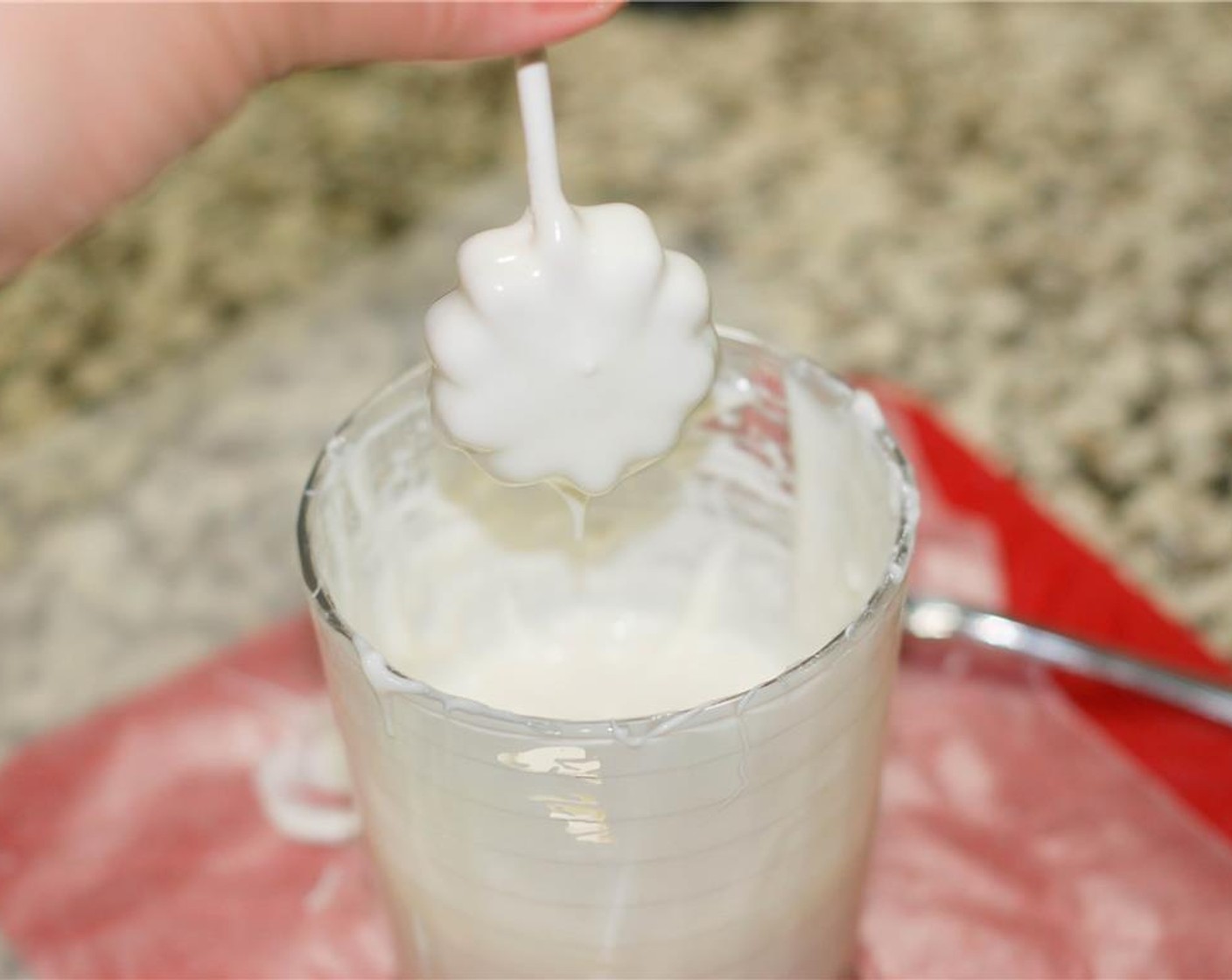 step 8 Remove a small batch of cookie dough pops from the freezer and dip them in the candy melt. Swirl them around upside down a bit to remove any excess candy melt, then place them upright in a pop holder until the candy melt hardens. Repeat.