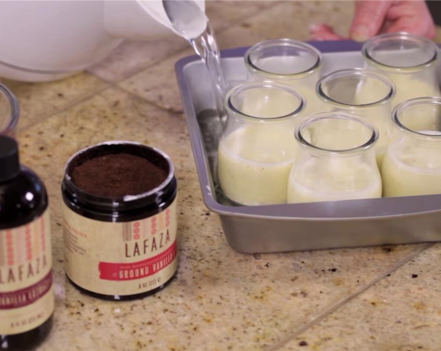 step 7 Place the filled pot de creme cups in a deep baking pan. Create a water bath by filling the pan with warm water to halfway around the cups. Cover the cups with a sheet of plastic wrap.