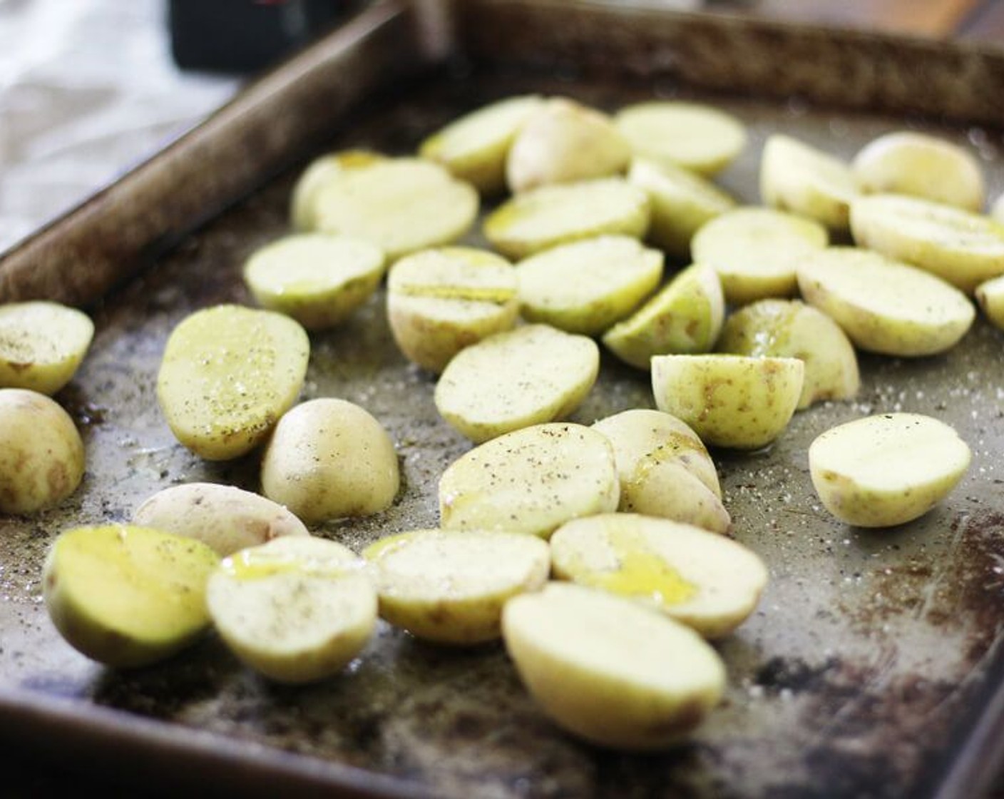 step 7 On a rimmed baking sheet, toss the baby potatoes with Olive Oil (1 Tbsp) and season with Salt (1/4 tsp) and Ground Black Pepper (1/4 tsp).