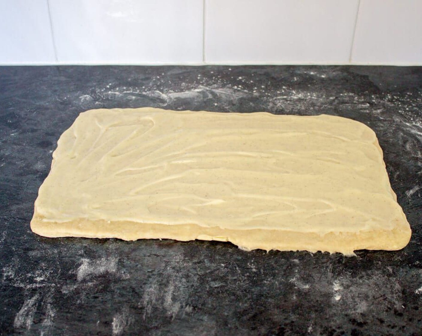 step 21 To assemble, halve the dough and roll out one of them to a rectangle with a long side towards you. Spread half of the creme patissiere over it leaving a clear 5cm margin on the long edge nearest to you.
