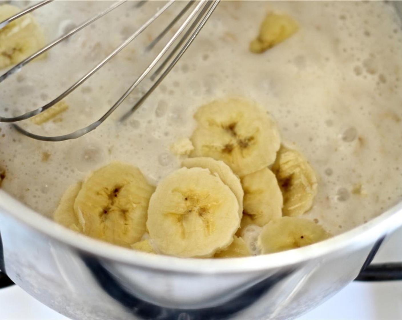 step 2 Thinly slice the medium Banana (1/2) and whisk it in, "whipping" the oatmeal to a creamy texture. Add more milk if needed to achieve the desired consistency. Continue cooking for another 3-5 minutes, or until the oats are creamy.