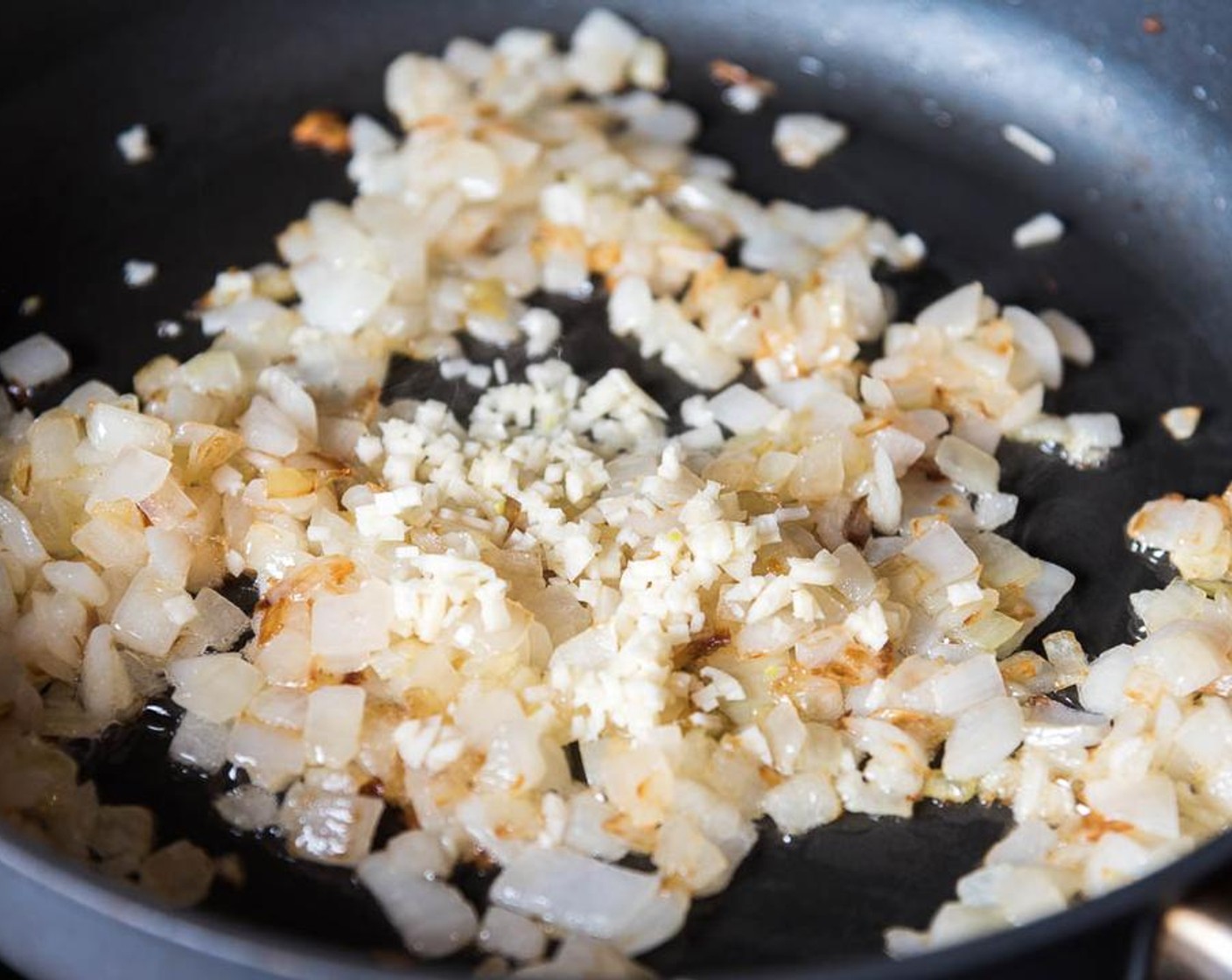 step 2 Heat Peanut Oil (2 Tbsp) in a large skillet over medium heat until warm. Mince the White Onion (1) and add to the skillet.  Cook and stir until translucent and the edges are lightly brown for 8 to 15 minutes.