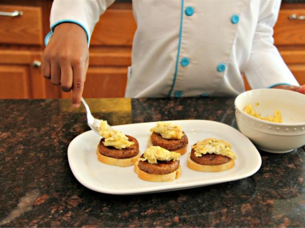 Step 6 of Sausage and Egg Breakfast Stacks Recipe: Place the sausage on the toasted bread then spoon eggs on top.
