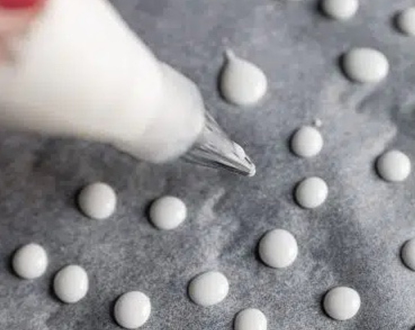 step 2 Transfer the sugar paste into a piping bag with a 3 mm round hole nozzle. Pipe 1-1.5 cm dots onto a baking tray lined with parchment paper. Repeat until all the sugar paste has been used up.