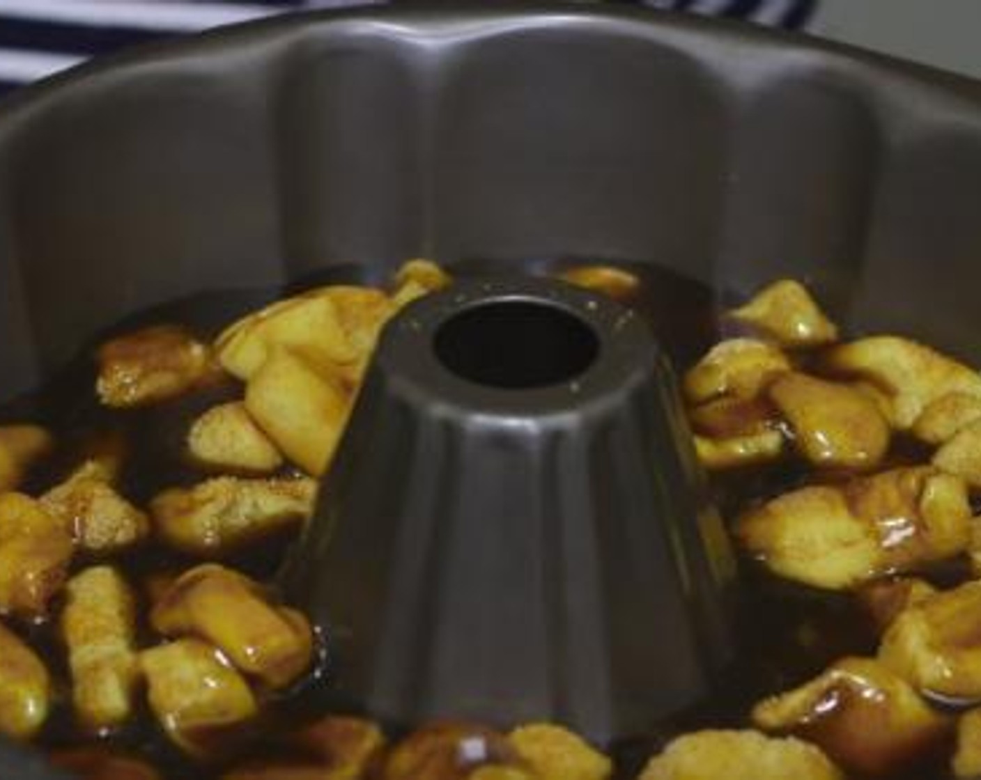 step 5 Put half of the caramel sauce inside a cake pan, then place the dough pieces, and pour over the remaining sauce on top. Cover the pan with a plastic cover and let it rise for about 30 minutes.