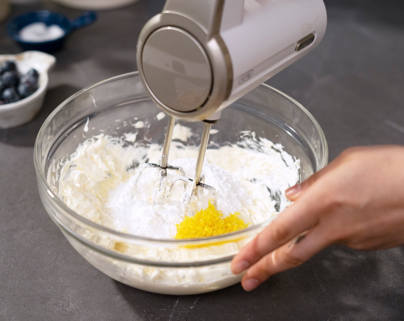 step 4 In a large mixing bowl, beat Cream Cheese (2 cups) with a hand mixer until smooth. Add Powdered Confectioners Sugar (1/2 cup) and zest of a Lemon (1). Beat until smooth on low to medium speed. Use a spatula to scrape down the sides to ensure the mixture is fully incorporated.