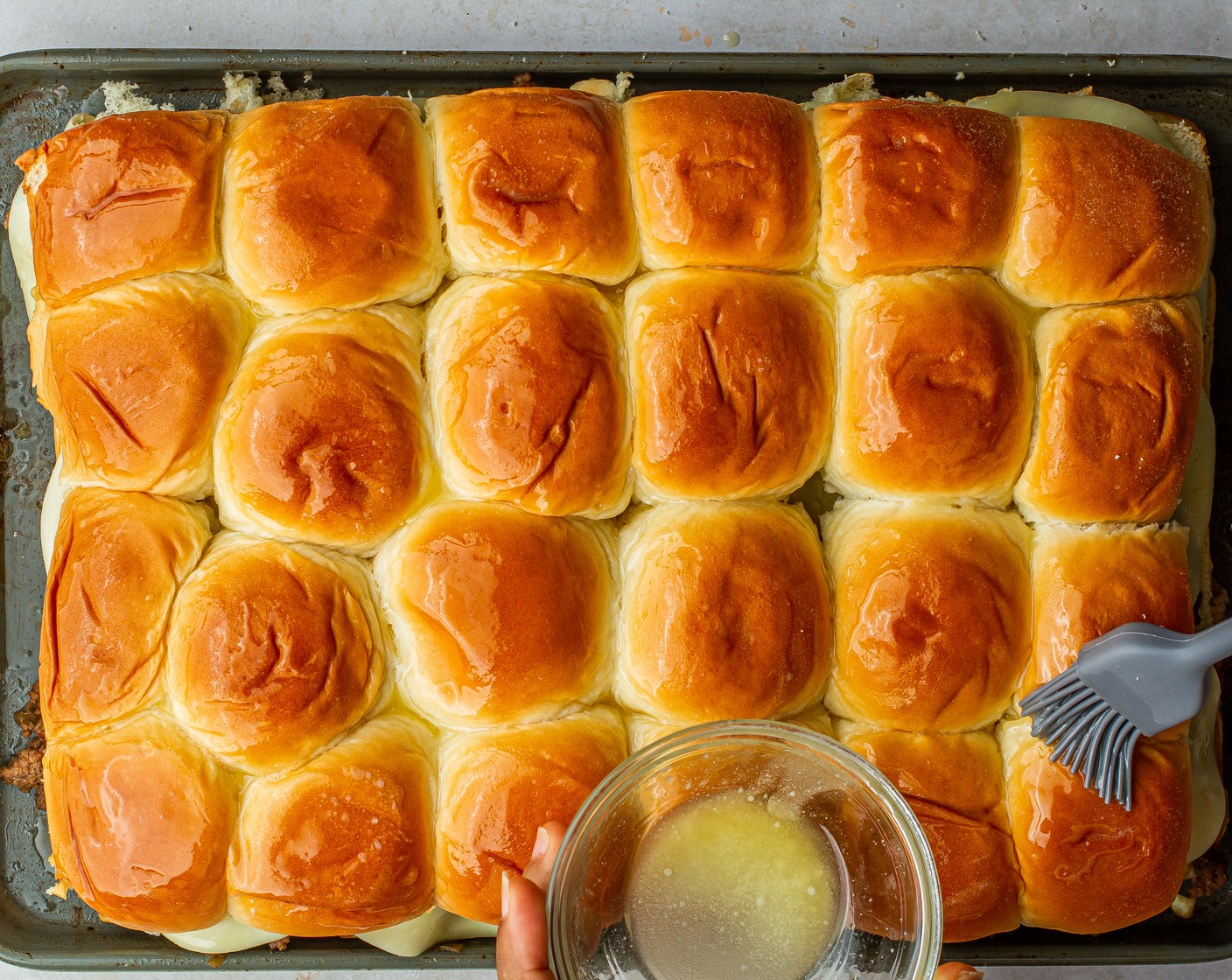 step 9 Place the top buns over the top and brush with melted butter. Transfer sheet pan to the oven and bake for 20 minutes or until the cheese is melted and the top buns are lightly browned. Serve warm.