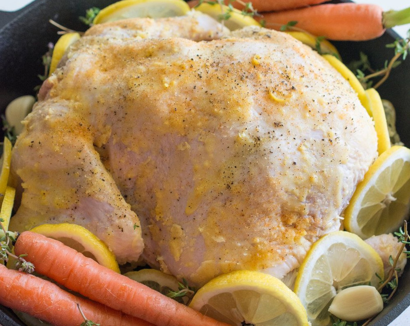 step 7 Slice the other Lemon (1) into thin slices. Place lemon slices around the chicken, then place Carrots (4), Garlic (10 cloves) and Fresh Thyme (6 sprigs) all around the chicken.
