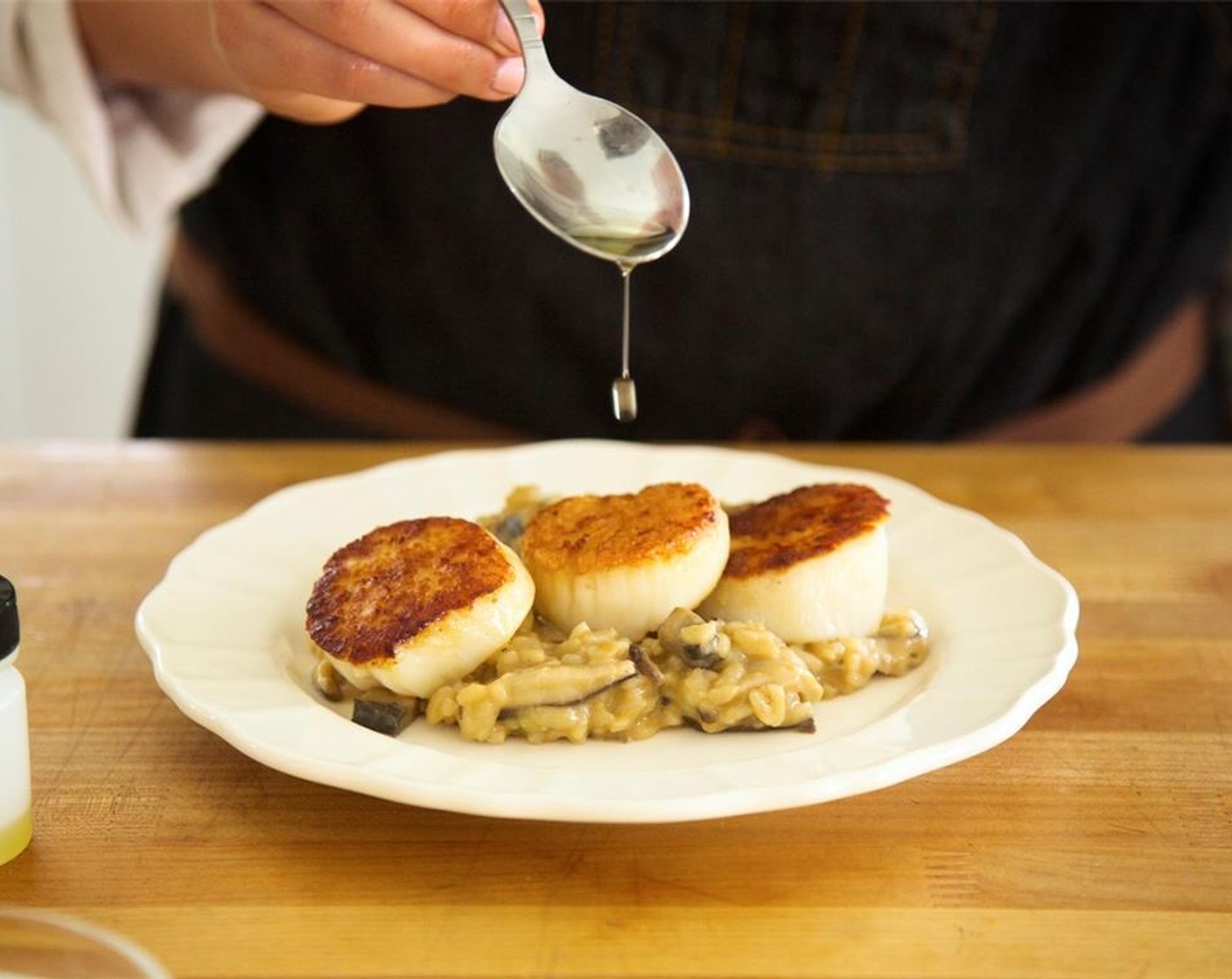 step 15 Distribute risotto in the middle of each plate and place three scallops directly on top of risotto in a single line. Lightly drizzle White Truffle Oil (1 tsp) evenly over every scallop and the risotto. Garnish with remaining minced chives.