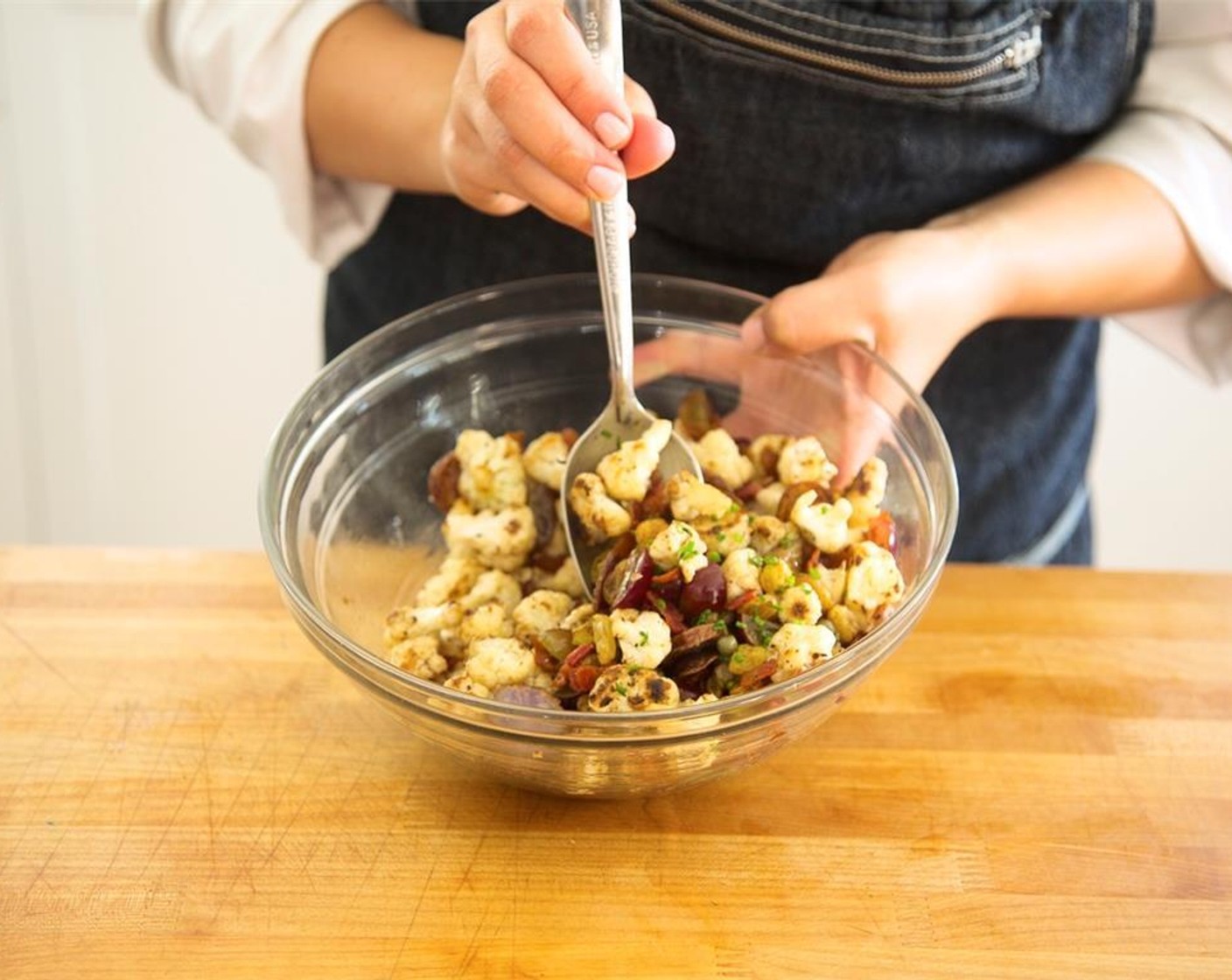 step 17 Place the cauliflower, celery, bacon, and potatoes in a large bowl with raisins and grapes. Add Capers (1 Tbsp) and half of the chopped chives. Season with Salt (1/2 tsp), Ground Black Pepper (1/4 tsp) and Olive Oil (1 Tbsp). Toss gently.
