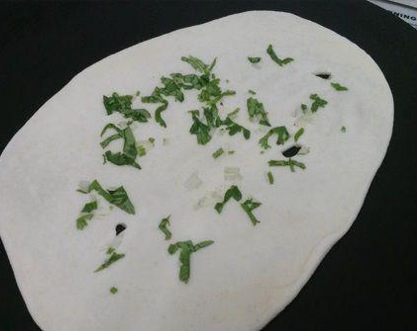 step 3 You can just make plain naan. But here I added some Ground Coriander (2 Tbsp) and Garlic (1 Tbsp) on top. Now using the rolling pin slightly press the coriander leaves and garlic. Now reverse the rolled naan and on the other side brush water. We need and iron tawa for making naan.  Non stick tawa wont work here.  As the naan will not stick properly on the non stick ones. To a hot tawa place the naaan, with the water brushed side down on the tawa.