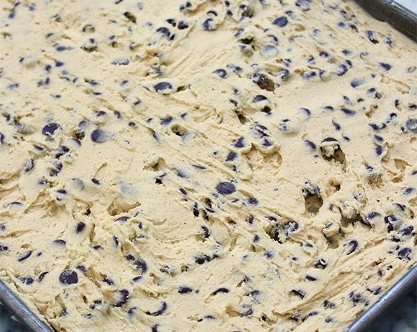 step 5 Spoon the cookie batter onto the prepared sheet pan and using a spatula, spread it into one even layer that covers the entire surface of the pan. Bake for 12-14 minutes, until lightly golden brown and still soft to the touch. The cookie should seem under-baked. Cool completely.