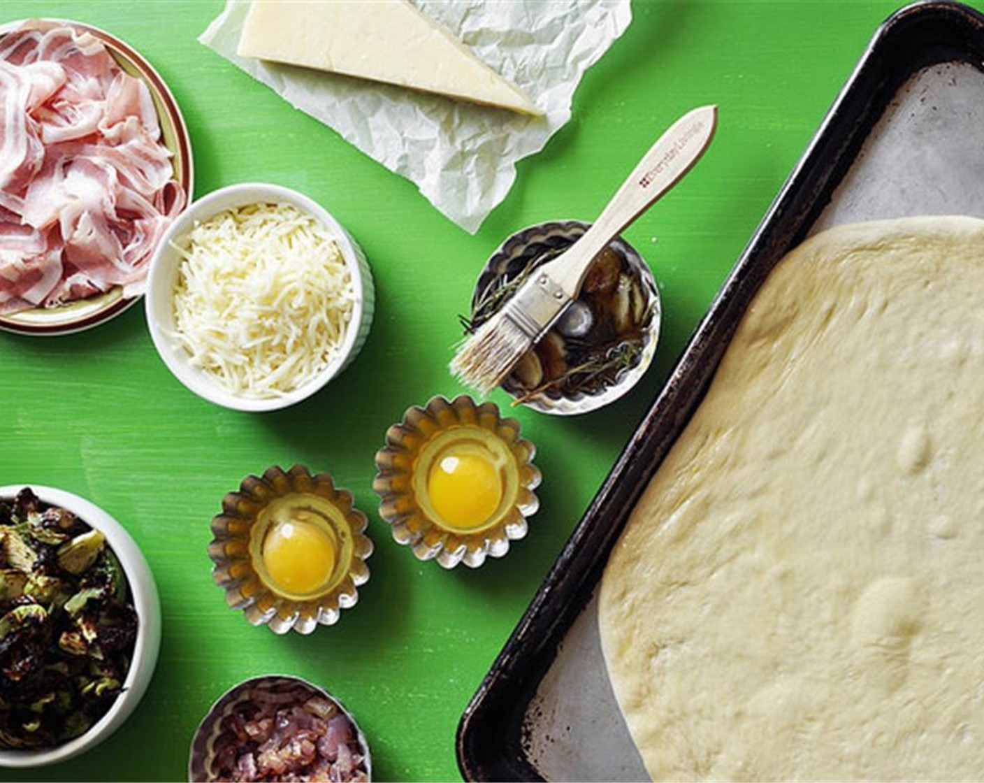 step 10 Cut the dough in half and roll each out on a lightly floured work surface. Roll into a large thin circle. Place each rolled crust onto two baking sheets. Brush the crusts liberally with the Garlic Herb Infused Oil (as needed) or Olive Oil (1 Tbsp).