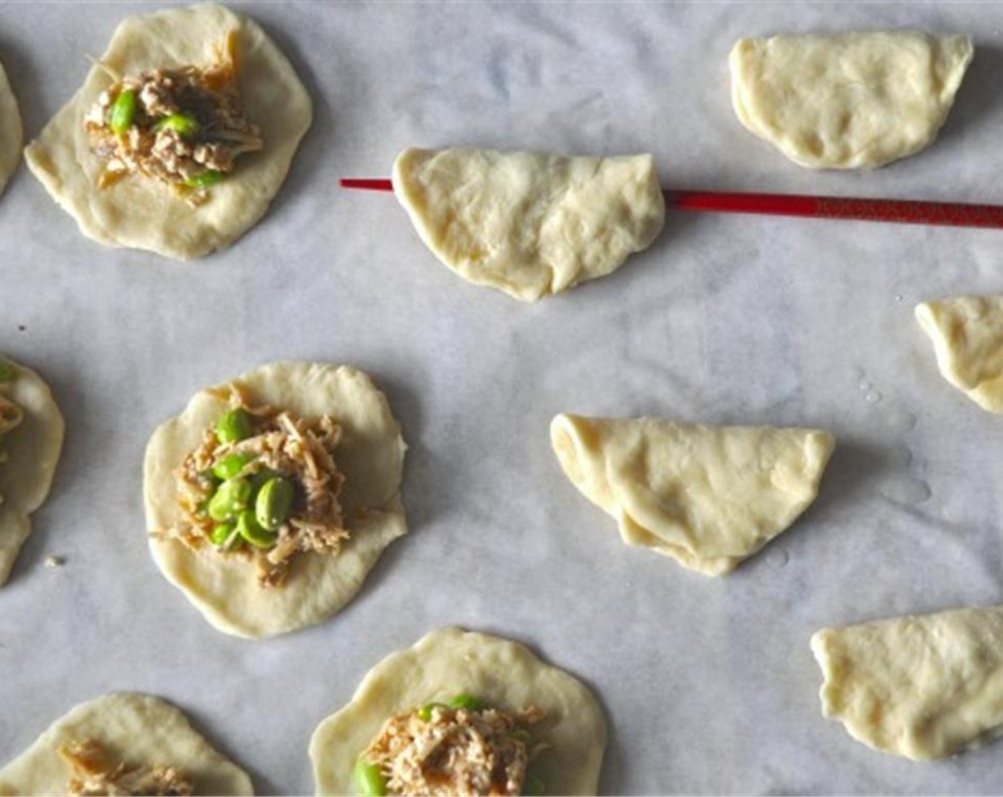 step 10 Place 1-2 tablespoons of filling on flattened bao dough and pinch shut. Place buns, seam side down on parchment paper, cover with plastic wrap and let rise 30 more minutes.