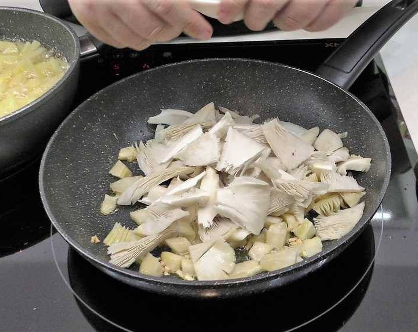 step 2 Heat another pan with Olive Oil (as needed) covering the bottom. Add the Garlic (3 cloves) and cook until it starts browning. Once the garlic starts browning add the Mushrooms (5) and Serrano Ham (1/4 cup).