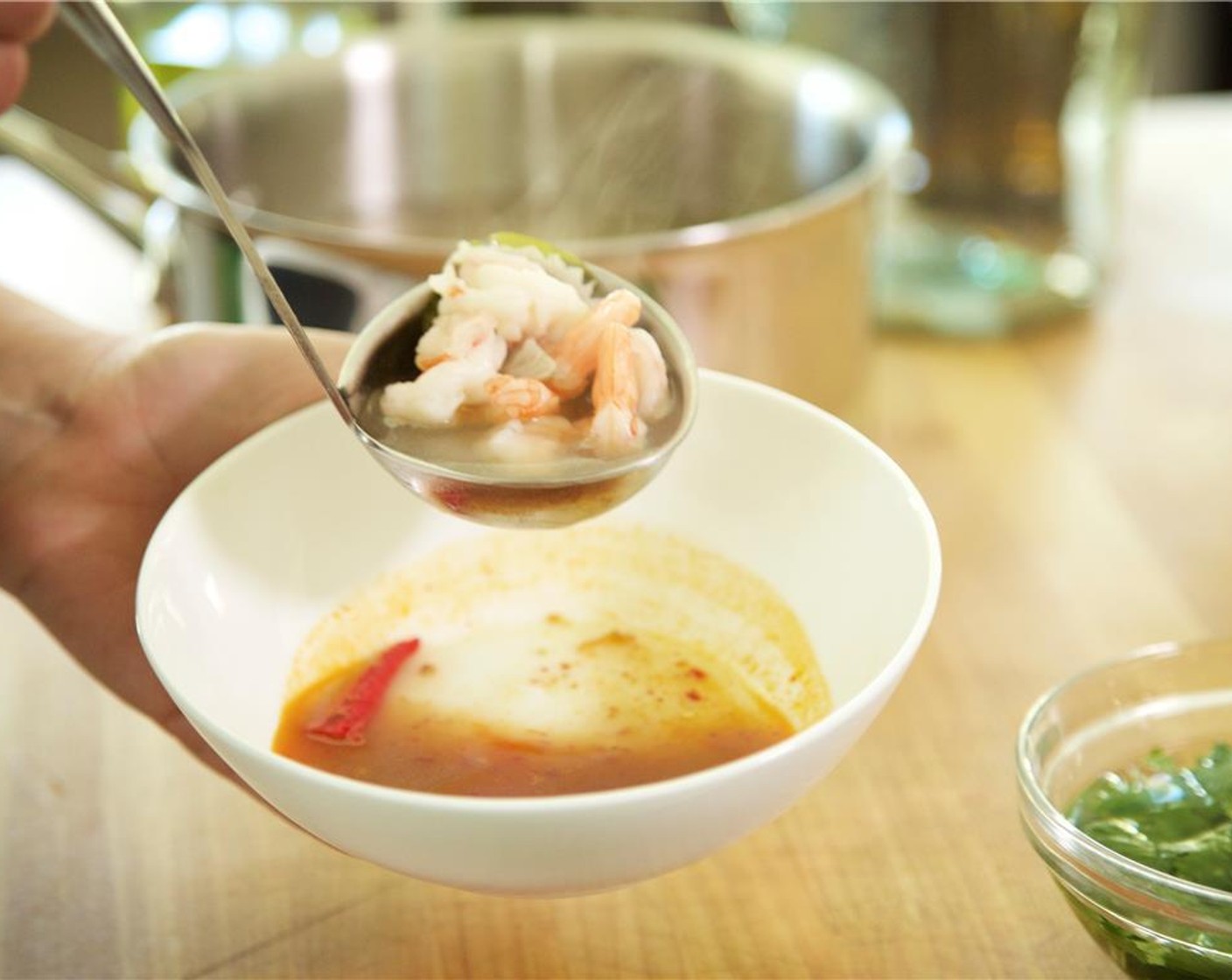 step 11 Cut the Limes (2) in half and juice them evenly between two bowls. Divide the Pantai Chili Paste (1 Tbsp), Fish Sauce (2 Tbsp), and thai chili peppers into the bowls. Ladle the soup gently into each bowl, evenly distributing the shrimp.