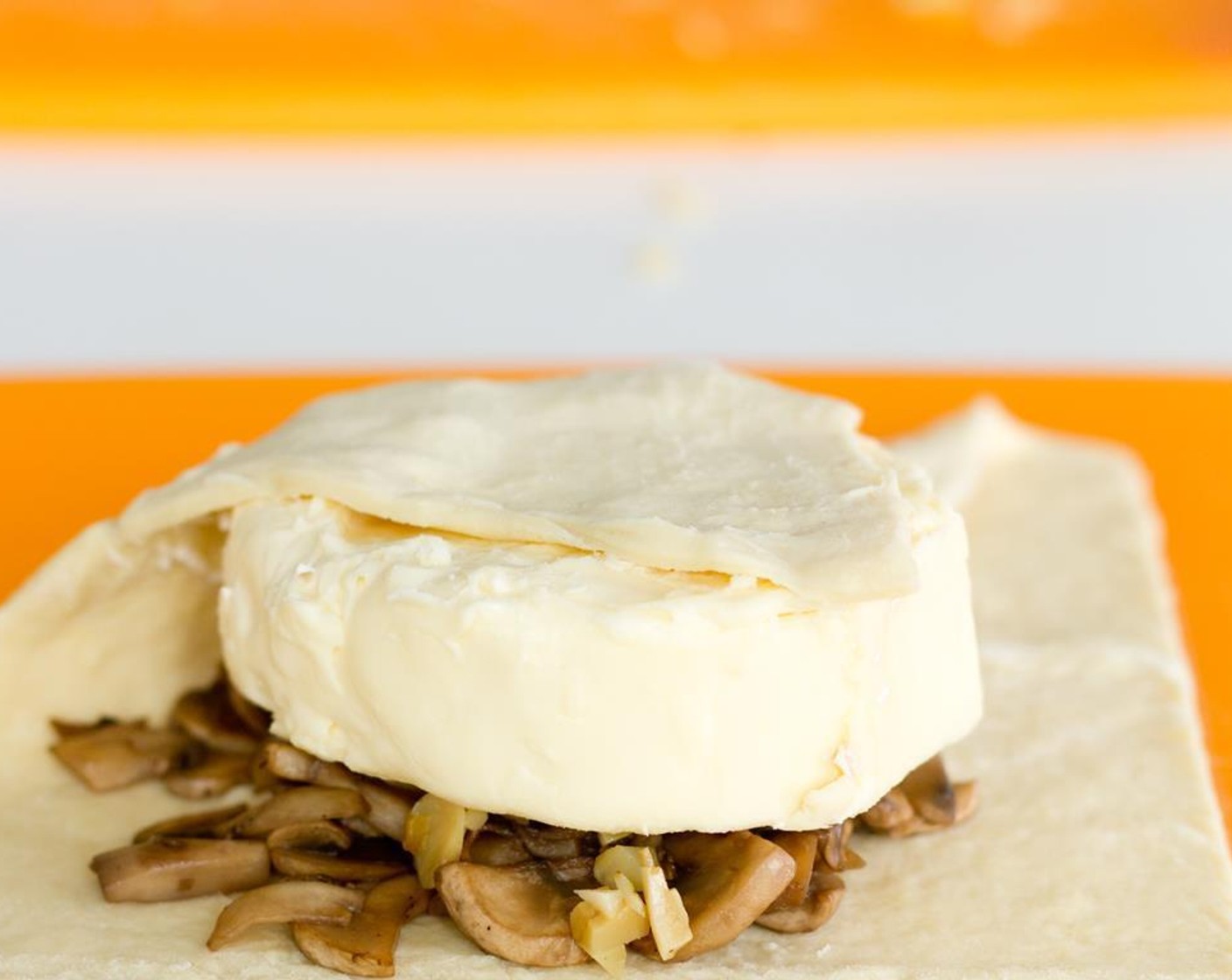 step 5 Lightly dust a cutting board with the All-Purpose Flour (2 Tbsp). Unfold and place Puff Pastry (1 pckg) on the surface. Place the prepared mushrooms in the center of the pastry and then stack the brie on top of it.