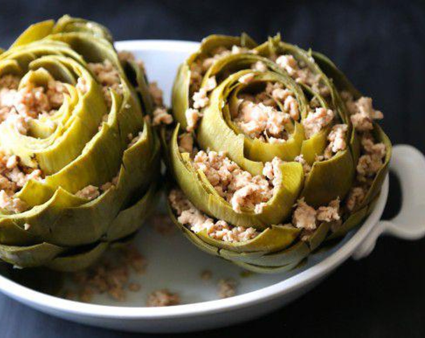 step 4 Spray a small baking pan with non-stick cooking spray. Place the artichokes into the baking pan and splay the leaves, sprinkling the Ground Chicken (8 oz) in between the layers.